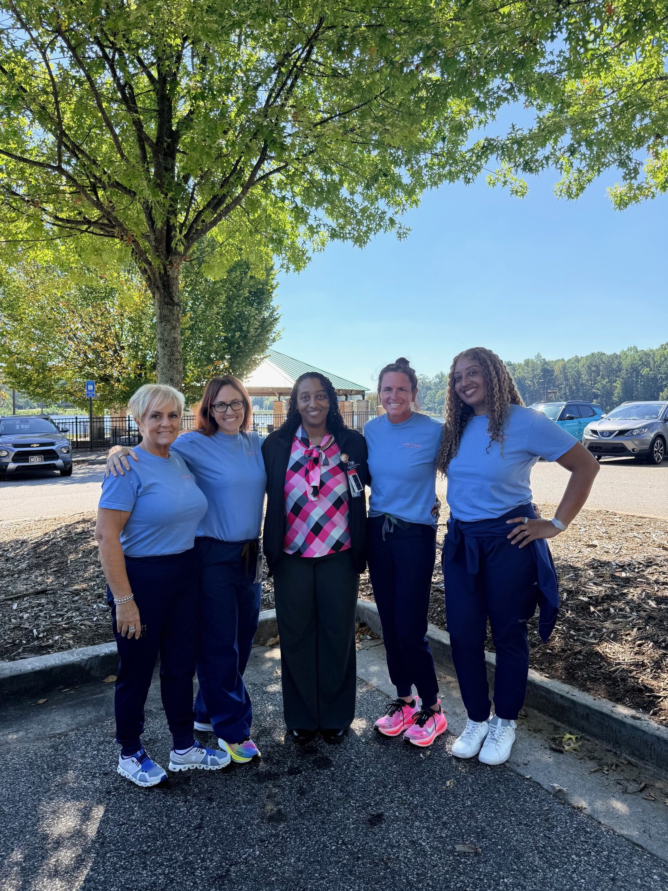 Five members of the CarFit team pose together outdoors in matching blue tops.
