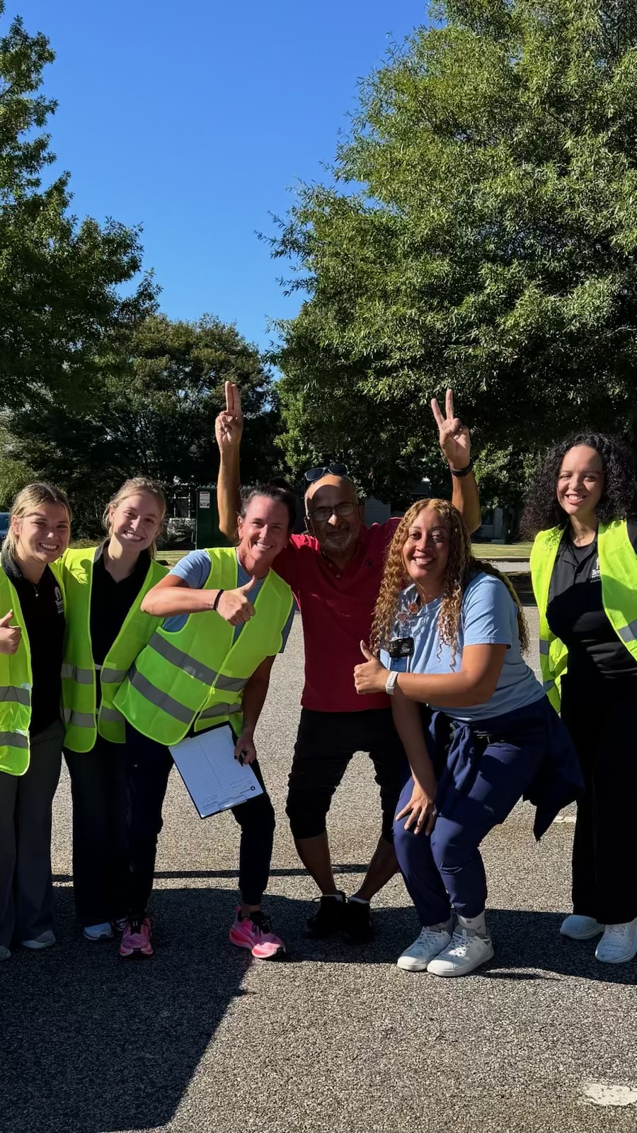 Brenau University occupational therapy students and event staff in safety vests cheer with arms raised.